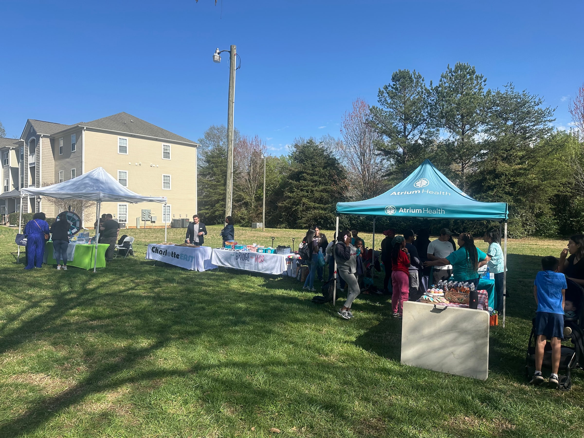 Residents connecting with local service providers at Rosecroft, with apartment homes behind the resource fair and an Atrium Health tent